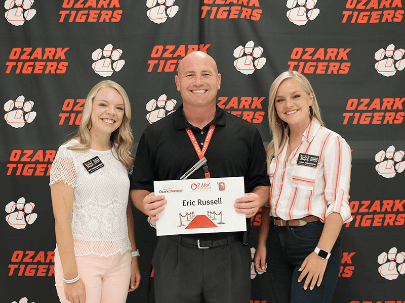 Torgerson Design Partners employees smiling in front of Ozark Tigers backdrop