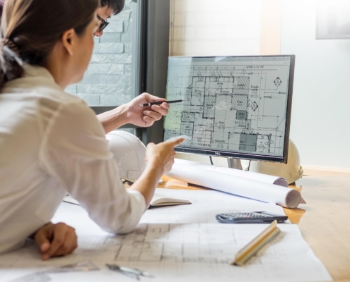 Architectural engineers looking at floorplans on computer