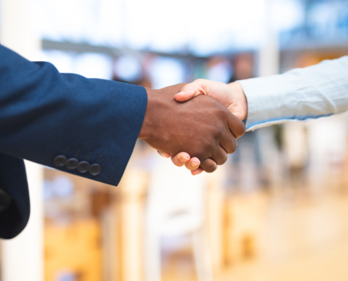 Side view of a man in a blue blazer and someone in a blue dress shirt shaking hands