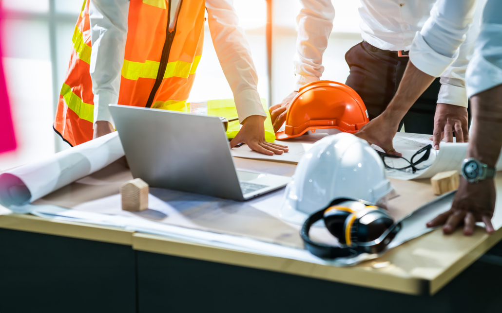 Side view of construction workers surrounding design blueprints